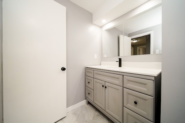 bathroom with marble finish floor, vanity, and baseboards