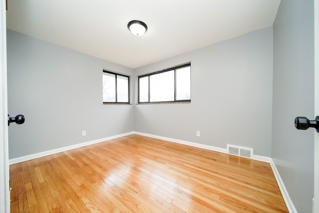 unfurnished room with light wood-style floors, visible vents, and baseboards