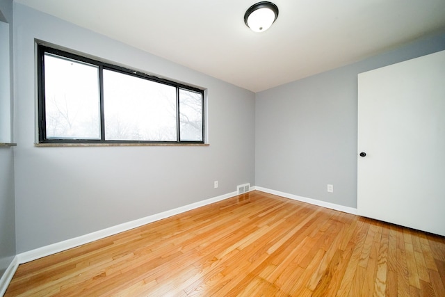 empty room with visible vents, baseboards, and hardwood / wood-style flooring