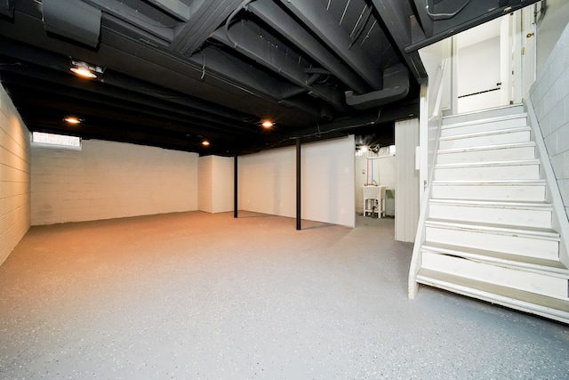 finished basement featuring stairs and a sink