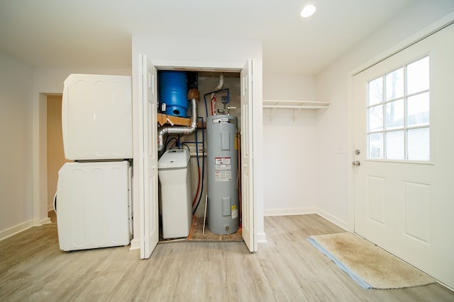 utility room featuring stacked washer / dryer and electric water heater