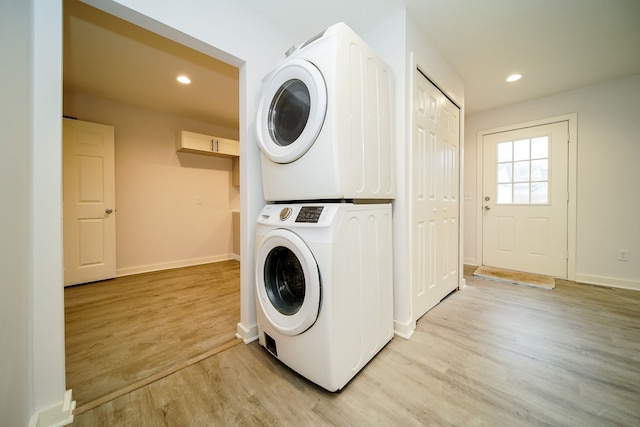 clothes washing area with baseboards, light wood finished floors, laundry area, recessed lighting, and stacked washer / drying machine