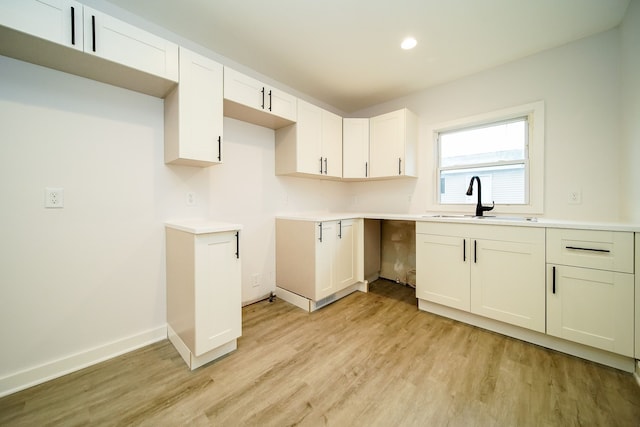 kitchen with baseboards, light wood-style flooring, recessed lighting, a sink, and white cabinetry