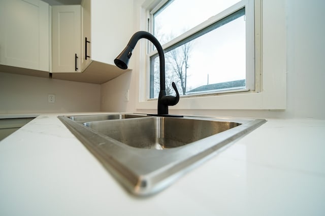 room details with white cabinetry, light countertops, and a sink