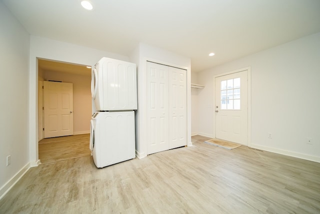 unfurnished bedroom featuring recessed lighting, light wood-type flooring, baseboards, and stacked washing maching and dryer