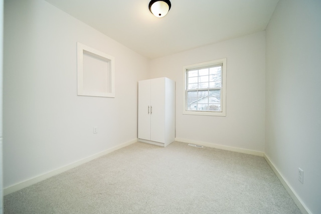 unfurnished room featuring light carpet, visible vents, and baseboards