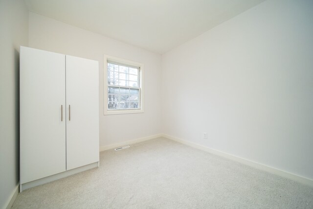 unfurnished bedroom featuring visible vents, baseboards, and light colored carpet