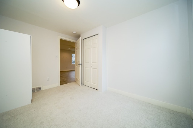 carpeted spare room with visible vents and baseboards