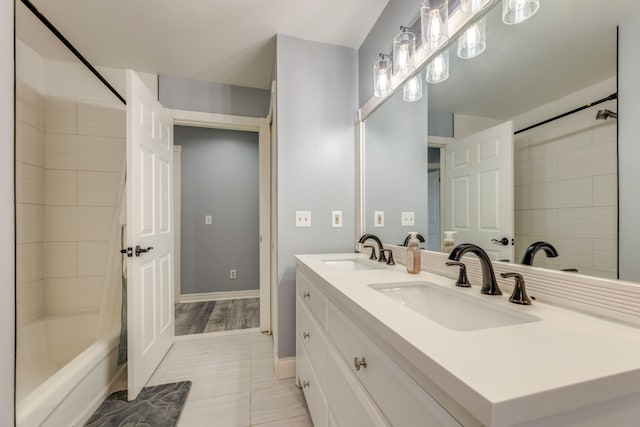 full bath featuring double vanity, shower / bath combination, baseboards, and a sink