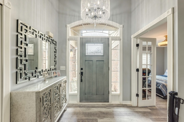 entrance foyer featuring french doors, a notable chandelier, and wood finished floors