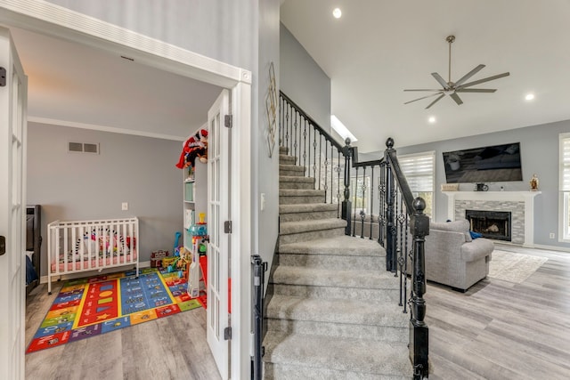 stairway with visible vents, crown molding, recessed lighting, a fireplace, and wood finished floors