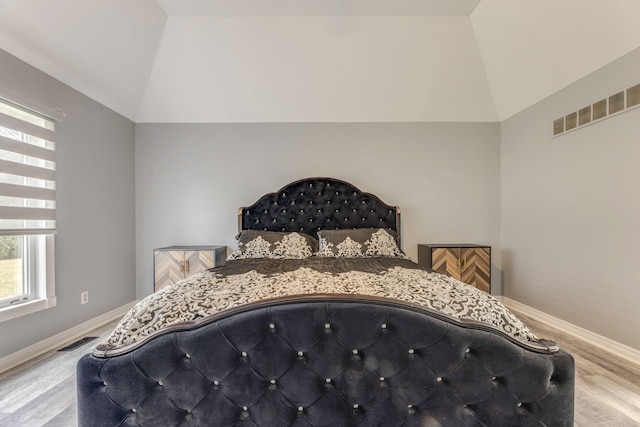 bedroom with visible vents, baseboards, wood finished floors, and vaulted ceiling