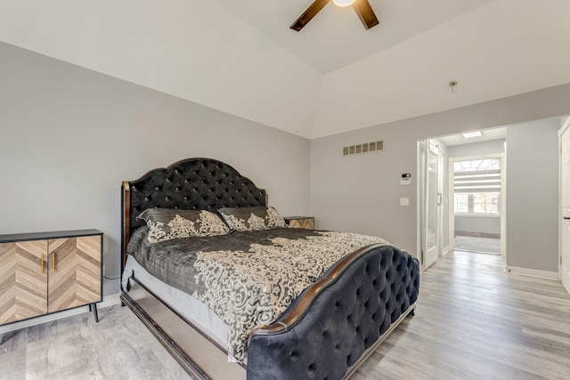 bedroom featuring a ceiling fan, visible vents, light wood finished floors, baseboards, and vaulted ceiling