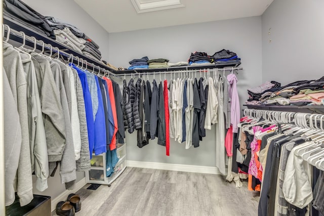 walk in closet with attic access and wood finished floors