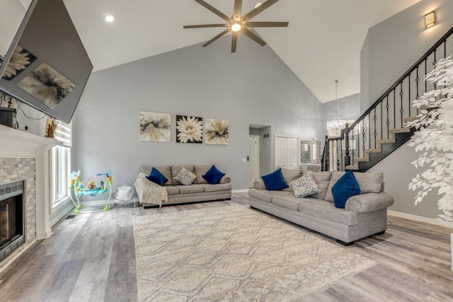 living area featuring a glass covered fireplace, stairway, wood finished floors, and baseboards