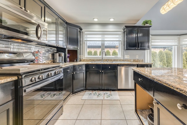 kitchen with light stone counters, light tile patterned floors, a sink, stainless steel appliances, and tasteful backsplash