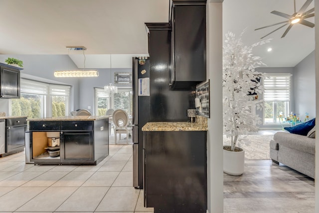 kitchen with light tile patterned floors, lofted ceiling, an island with sink, and ceiling fan