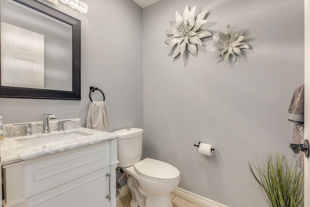 bathroom featuring baseboards, toilet, and vanity