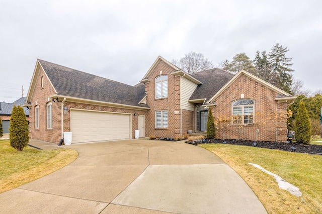 traditional-style home with driveway, a shingled roof, a front yard, an attached garage, and brick siding