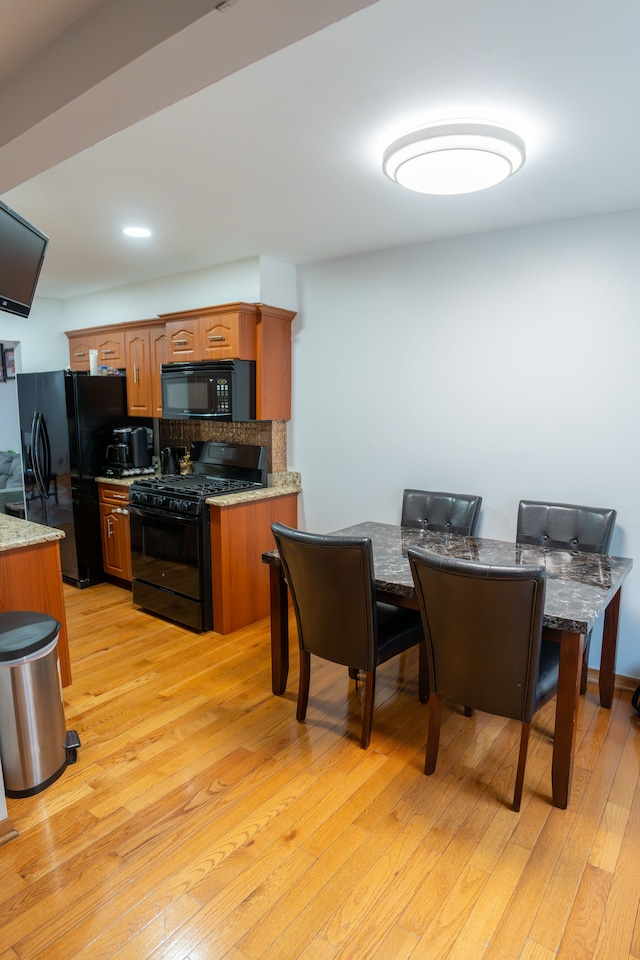 4468 15 Mile Rd Unit 104, Sterling Heights, MI 48310 - kitchen with black appliances, light wood-style floors, light stone counters, and brown cabinetry