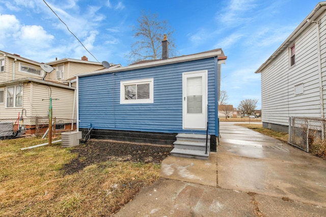 back of house featuring fence, central AC unit, driveway, and entry steps