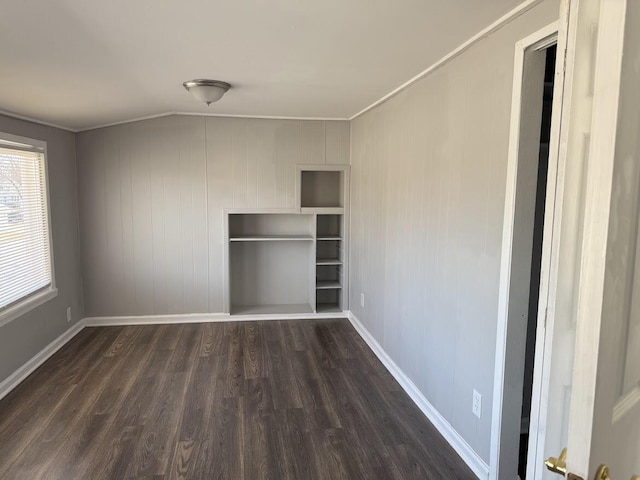 unfurnished room featuring baseboards, dark wood finished floors, and ornamental molding