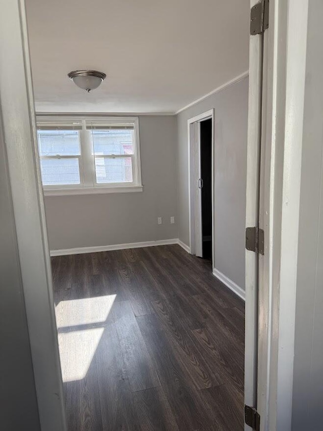 unfurnished bedroom with crown molding, dark wood-style floors, and baseboards