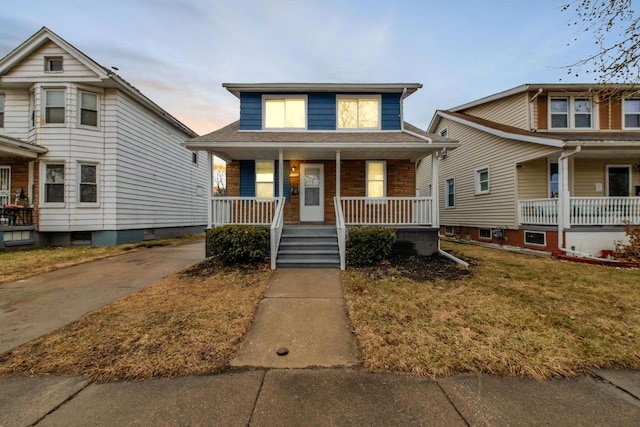 view of front of property featuring a porch, a shingled roof, and a front lawn