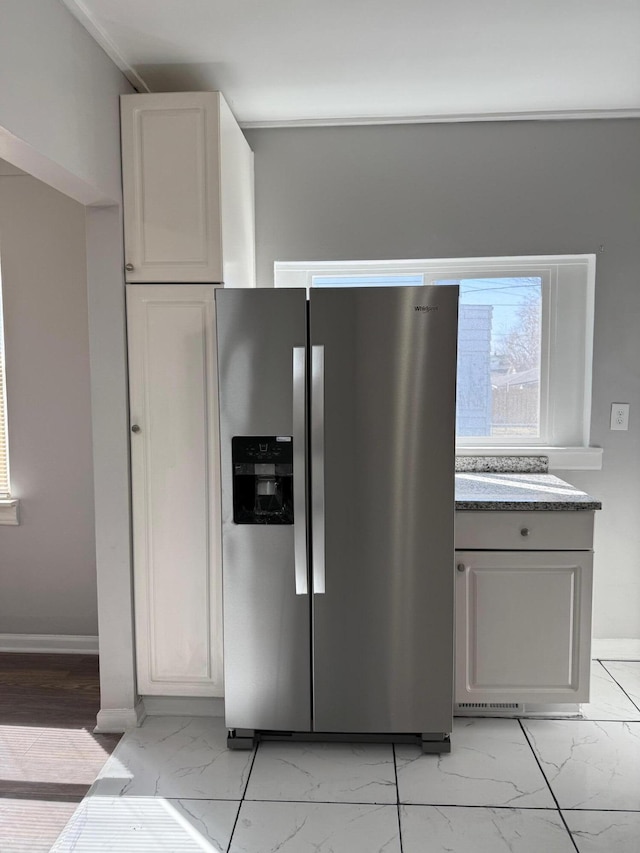 kitchen with stainless steel fridge with ice dispenser, marble finish floor, and baseboards