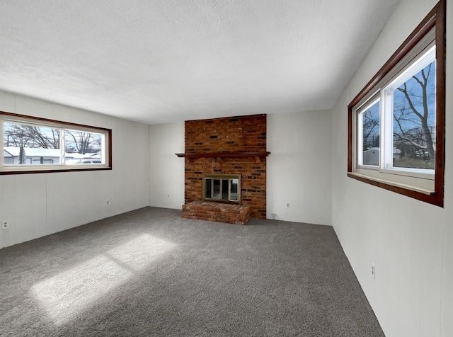 unfurnished living room featuring a textured ceiling, a fireplace, and carpet flooring