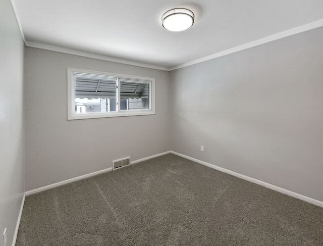 spare room featuring baseboards, visible vents, dark colored carpet, and ornamental molding