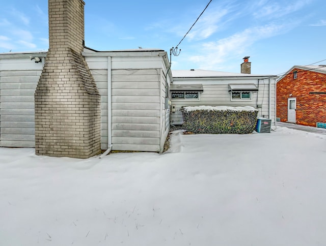 snow covered structure featuring central AC unit