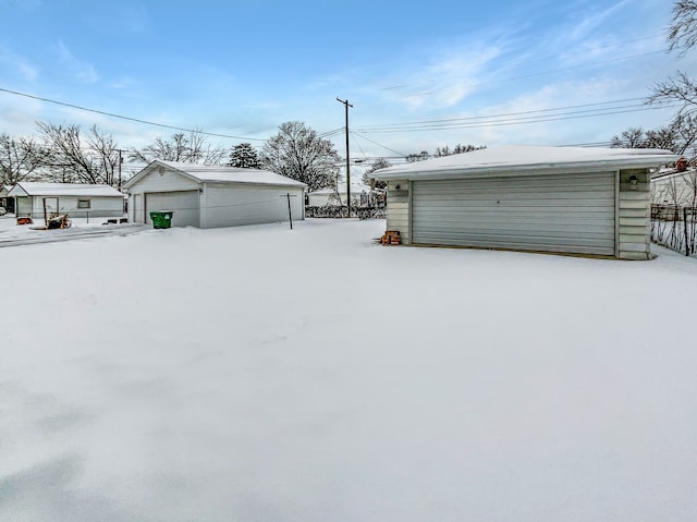 yard covered in snow with a garage, an outdoor structure, and fence