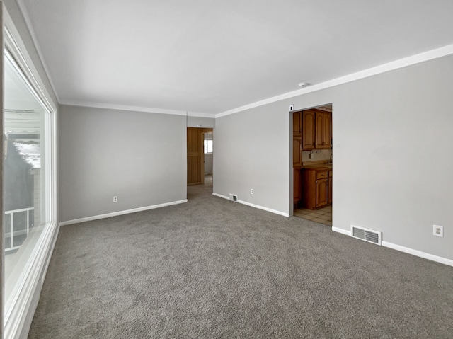 carpeted empty room featuring visible vents, baseboards, and ornamental molding