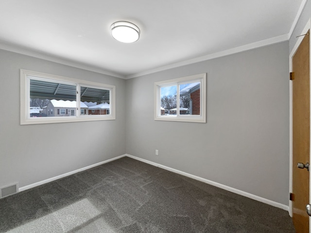 empty room featuring baseboards, visible vents, dark carpet, and ornamental molding