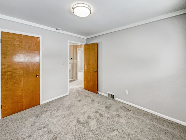 spare room featuring visible vents, carpet flooring, baseboards, and ornamental molding