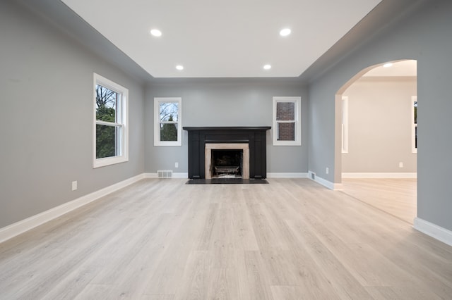 unfurnished living room with recessed lighting, baseboards, arched walkways, and light wood-style floors