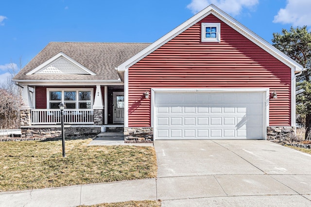 view of front of home with a shingled roof, concrete driveway, a front yard, covered porch, and stone siding