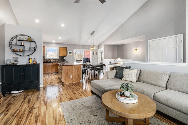 living area with recessed lighting, light wood-style floors, ceiling fan, and high vaulted ceiling