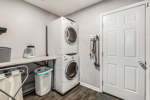 clothes washing area featuring stacked washer / drying machine, baseboards, dark wood-type flooring, and laundry area