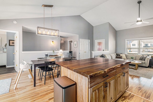 kitchen featuring open floor plan, light wood-style floors, butcher block counters, ceiling fan, and hanging light fixtures