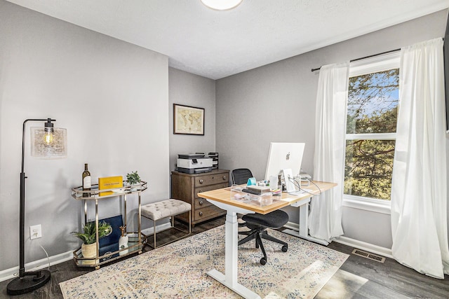 office area with wood finished floors, visible vents, and baseboards