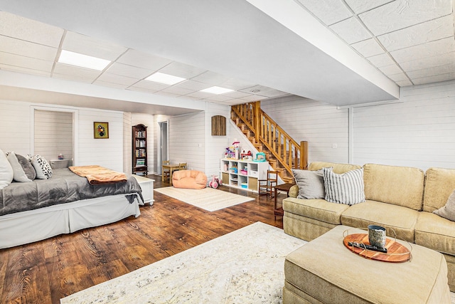 bedroom with a drop ceiling, wood finished floors, and wood walls