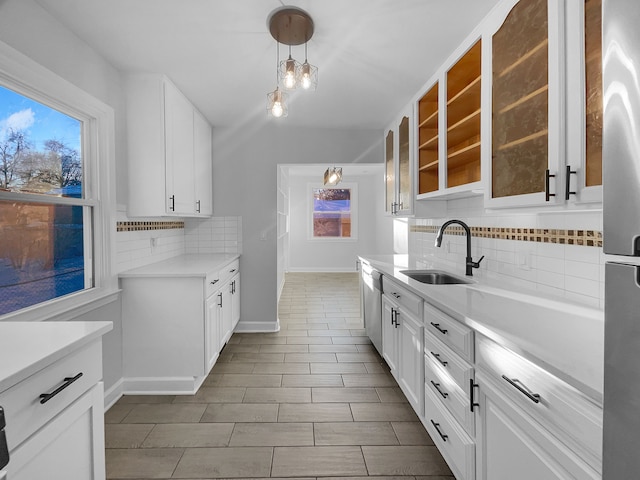 kitchen with glass insert cabinets, light countertops, appliances with stainless steel finishes, plenty of natural light, and a sink