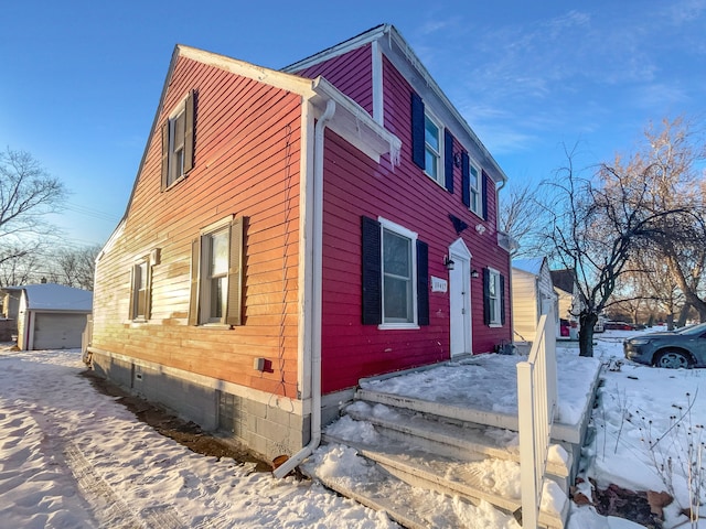 view of snowy exterior with a detached garage and an outdoor structure