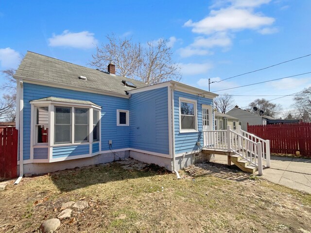 view of side of property with crawl space, a chimney, and fence