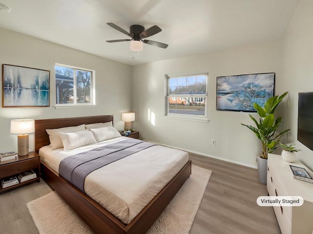 bedroom with multiple windows, baseboards, light wood finished floors, and ceiling fan