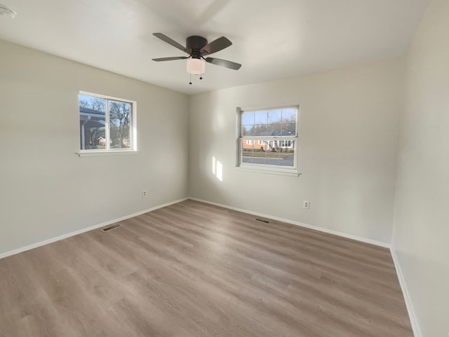 unfurnished room with visible vents, plenty of natural light, and wood finished floors