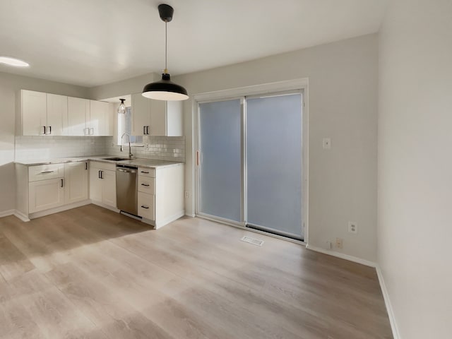 kitchen with dishwasher, decorative backsplash, light wood-style floors, white cabinets, and a sink