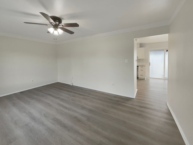 spare room featuring dark wood finished floors, a ceiling fan, baseboards, and ornamental molding